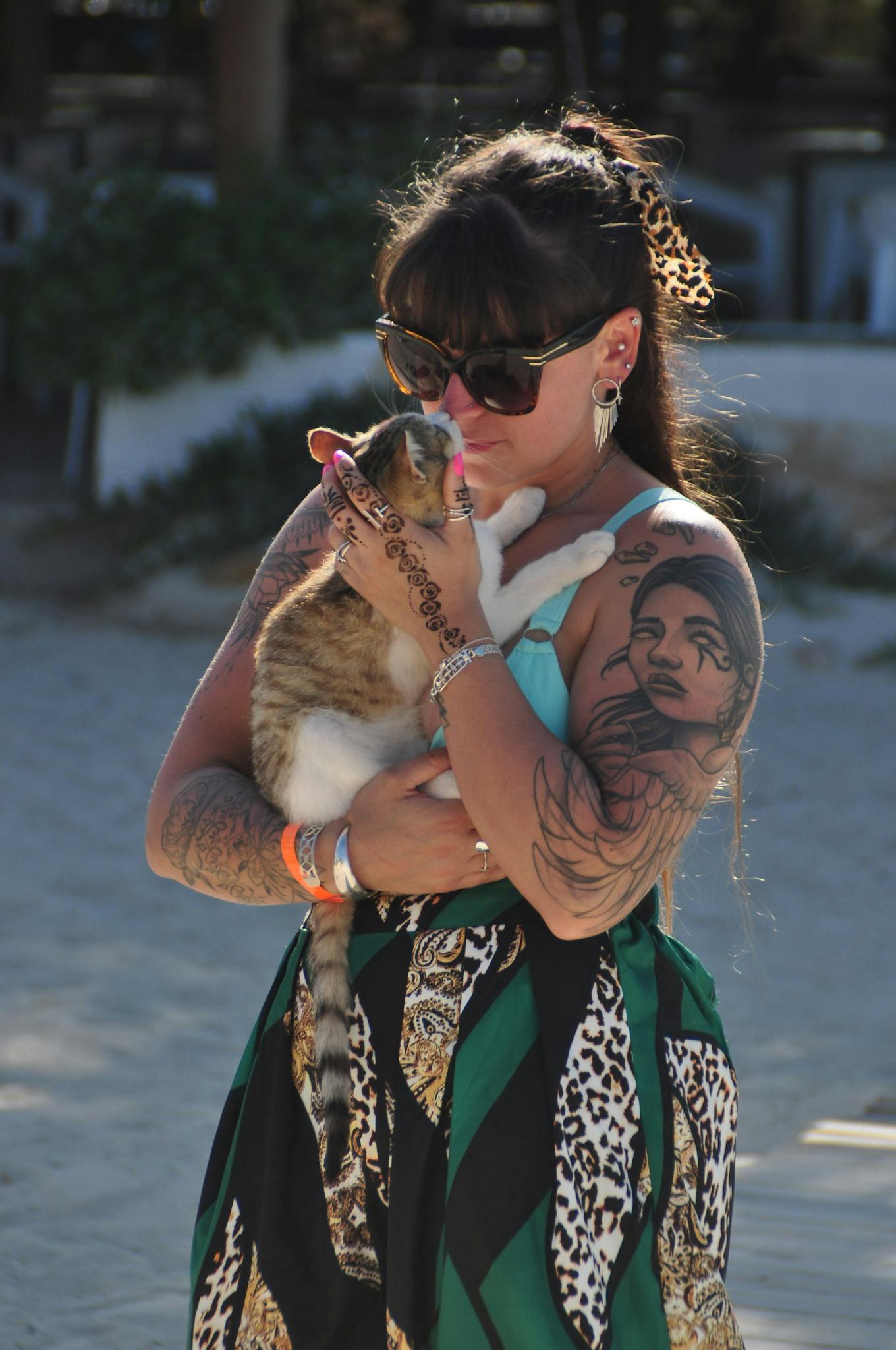 A woman with unique tattoos holding a cat outdoors in Médenine, Tunisia.